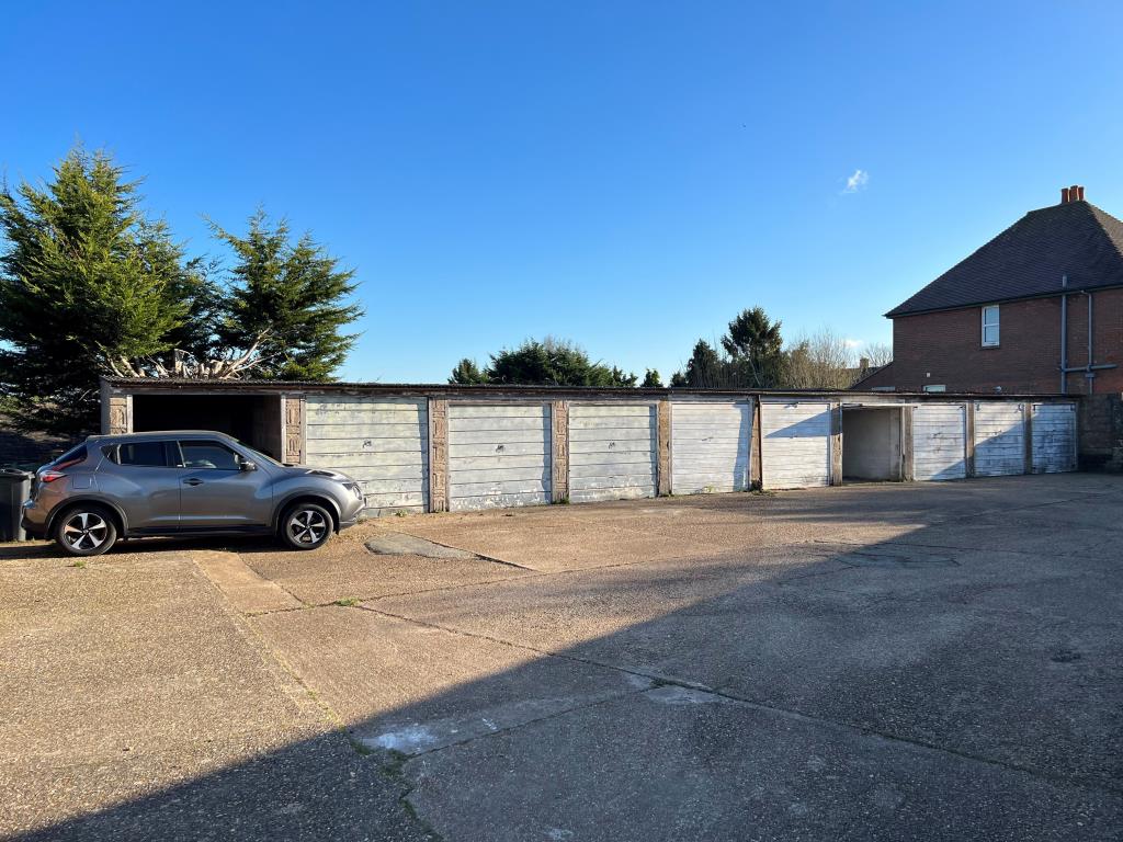 Lot: 83 - FREEHOLD BLOCK OF 19 GARAGES - Concrete hardstanding and turning area with garages in background